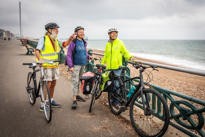 Three older people standing and talking with bikes