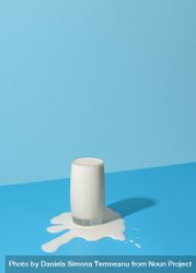 Overflowing glass of milk isolated on a blue background bG2Z24