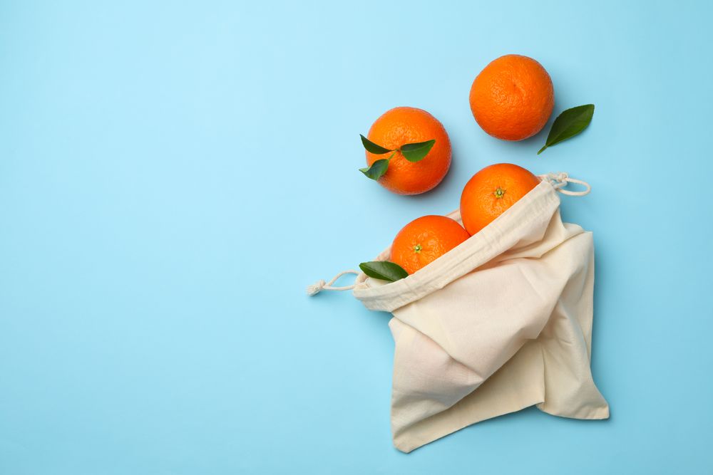 Cotton bag with ripe mandarins on blue background