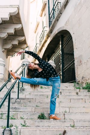 Casual woman dancing on old city street