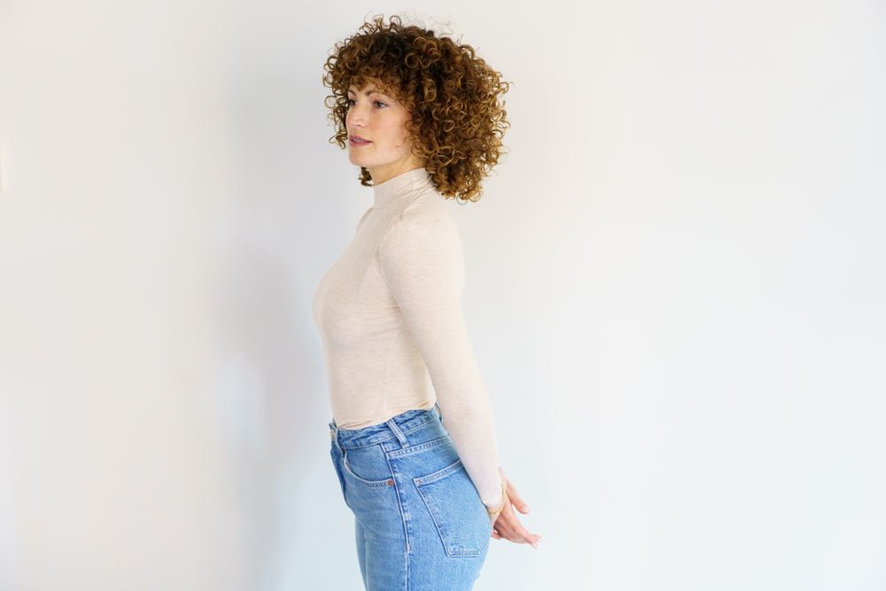 Side view of woman in casual clothes with arms behind her back