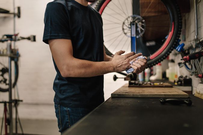 Worker cleaning his hands after repairing bicycle in workshop