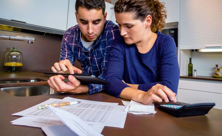 Male and female couple reviewing their monthly bills on kitchen counter