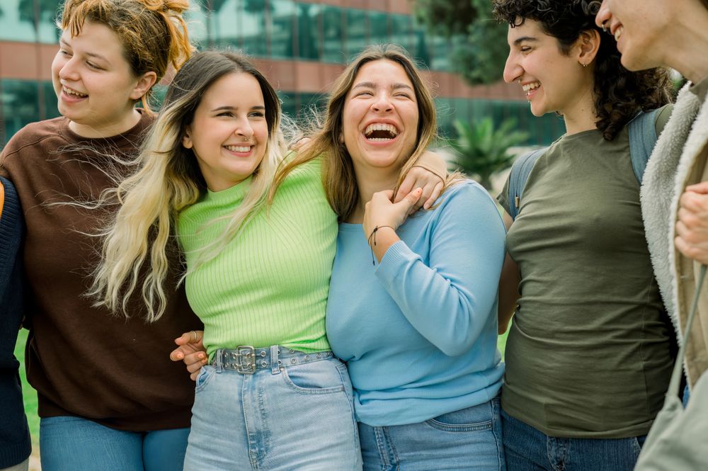 Group of diverse student friends hugging and laughing