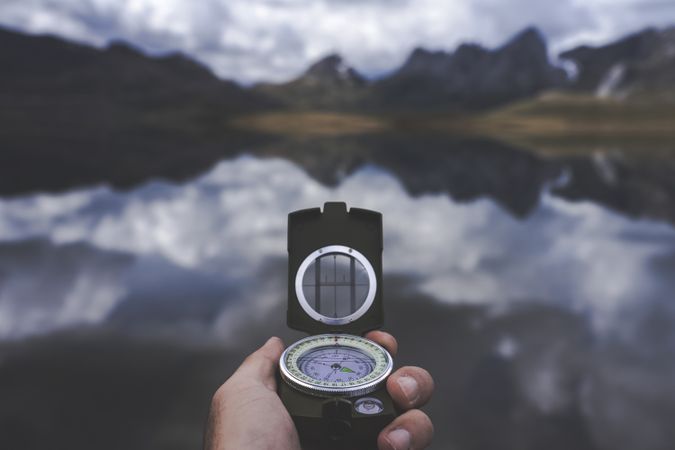 Crop hand with compass near lake