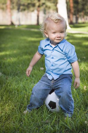 Young Cute Boy Playing with Soccer Ball in Park