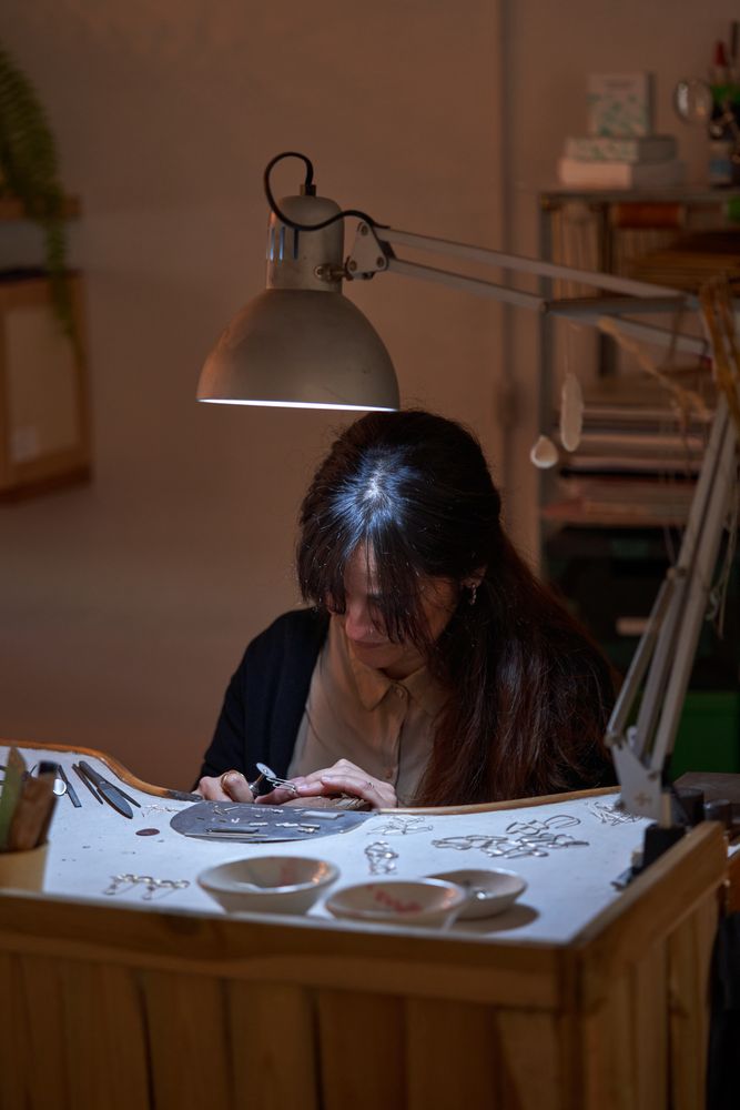 Focused female goldsmith using rotative tool while creating jewe