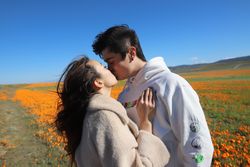 Man and woman kissing beside yellow flower field
