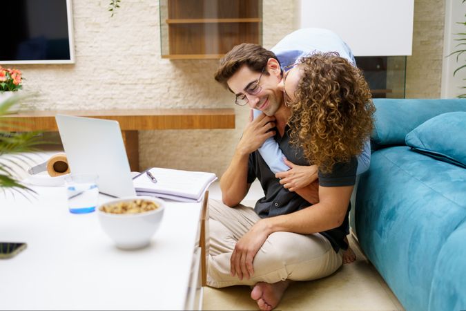 Affectionate couple working from home together in living room
