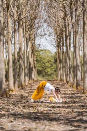 Cheerful mother and daughter practicing yoga in park during sunny day