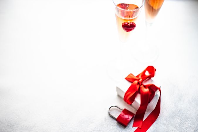 Two glasses of pink champagne with ribbon wrapped gift and copy space