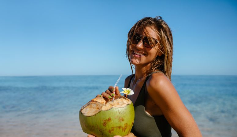 Beautiful woman with fresh coconut on the beach