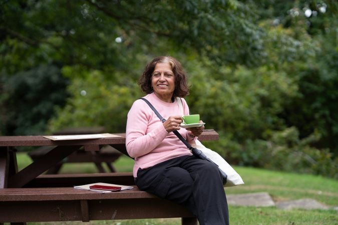 Older Indian woman sitting outside sipping tea