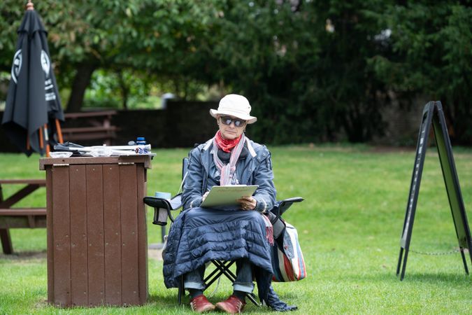 Older woman covered up in the sun during drawing class