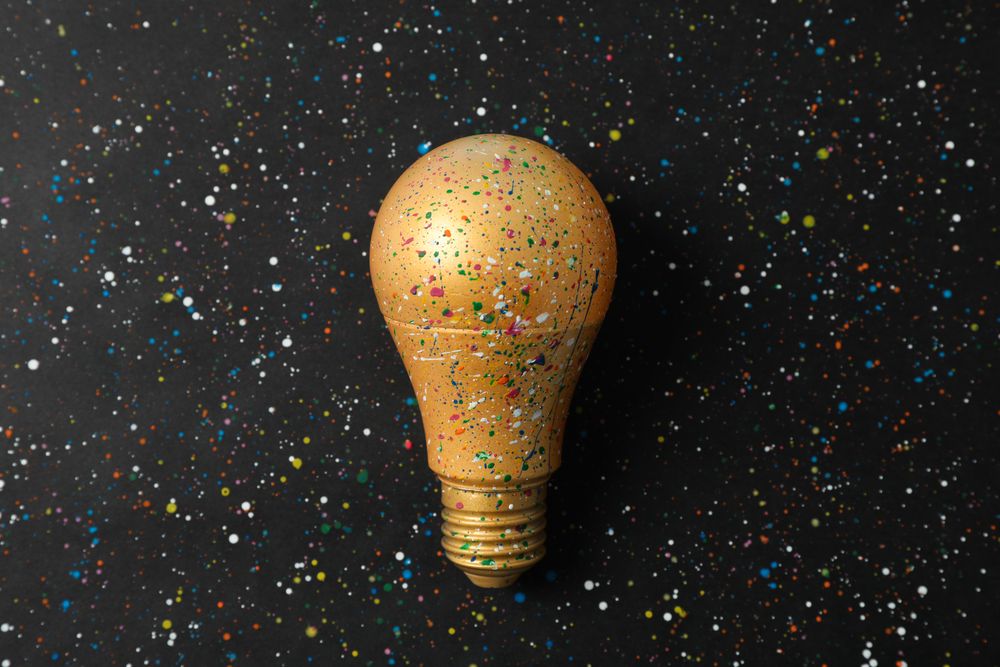 Paint splatters and spots on light bulb and dark background. Creative idea concept