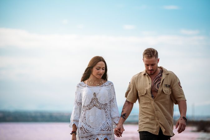 adorable couple walking on an amazing beach with pink water