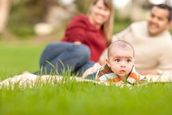 Happy Crawling Baby Boy and Parents Playing in the Park