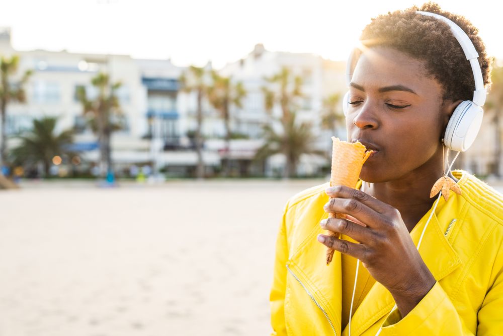 Cool female eating ice cream on beach