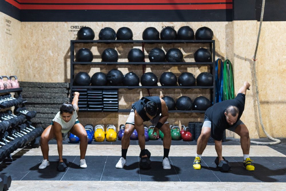 Hispanic sportspeople lifting kettlebells during powerlifting training