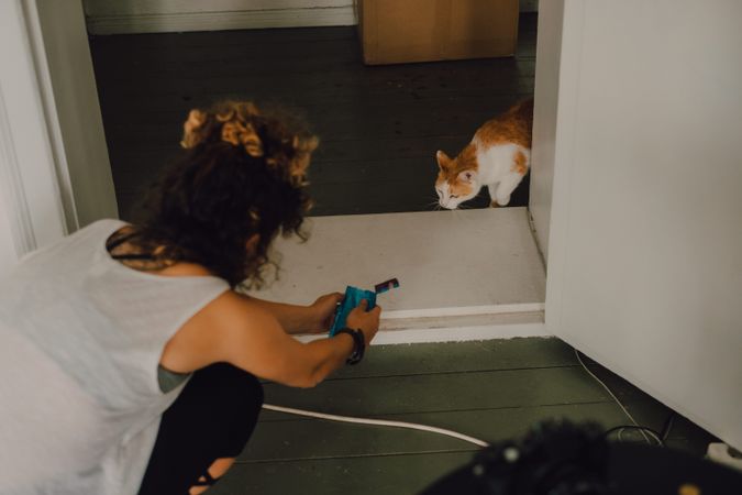 Woman feeding ginger cat at home