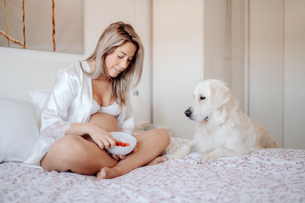 Pregnant woman eating fruits and resting with dog