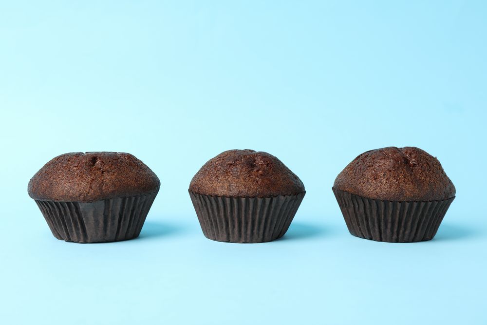 Delicious tasty chocolate muffins on blue background