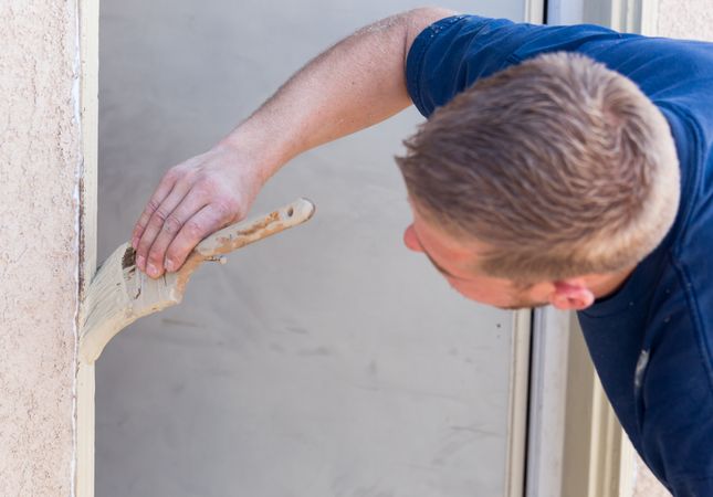 Professional Painter Cutting In With Brush to Paint House Door Frame.