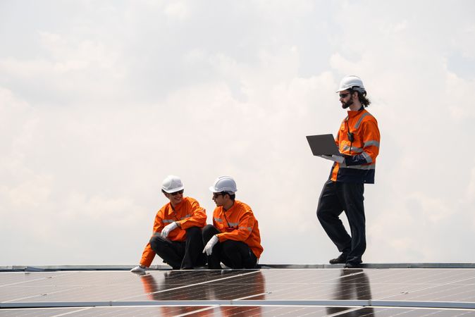 Engineer team checking solar cell  or photovoltaic cell installed on the roof of the factory. Technician worker repair or inspect the system. Industrial renewable energy concept