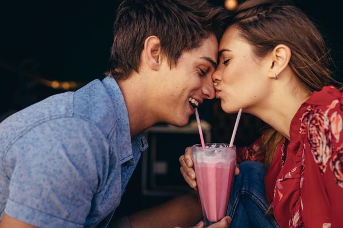 Woman kissing her boyfriend on his nose while on date at a restaurant