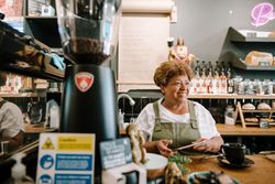 Smiling older Black woman with digital tablet in coffee shop
