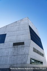 Grey modern building with unsymmetrical windows with blue sky, vertical bDdLEb