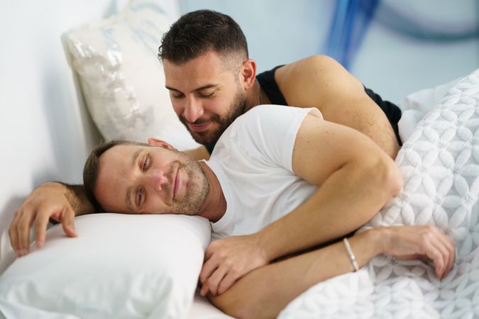 Cute male couple holding each other in bed