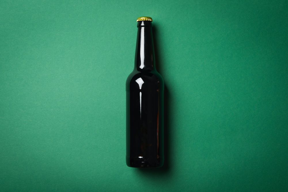 Bottle of beer on green background, space for text