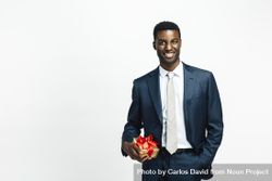 Professionally dressed Black man holding present wrapped in gold paper and red bow 4BnWd4