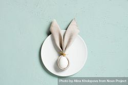 Bunny ear shaped napkin on plate on blue background with copy space 5nqQ80