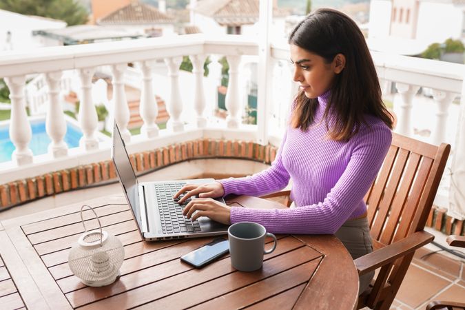 Woman sitting on deck working on computer