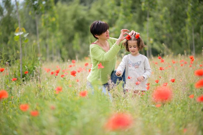 Woman putting poppies in little girl’s hair