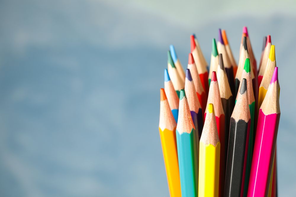 Multicolored pencils against light blue background, closeup