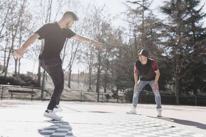Guy looking at man dancing break dance in park