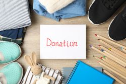 Text Donation, clothes and different accessories on wooden background, top view