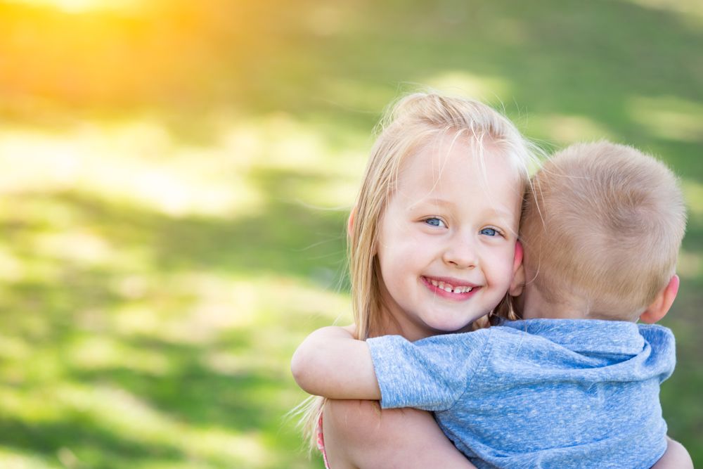 Young Brother and Sister Hugging At The Park