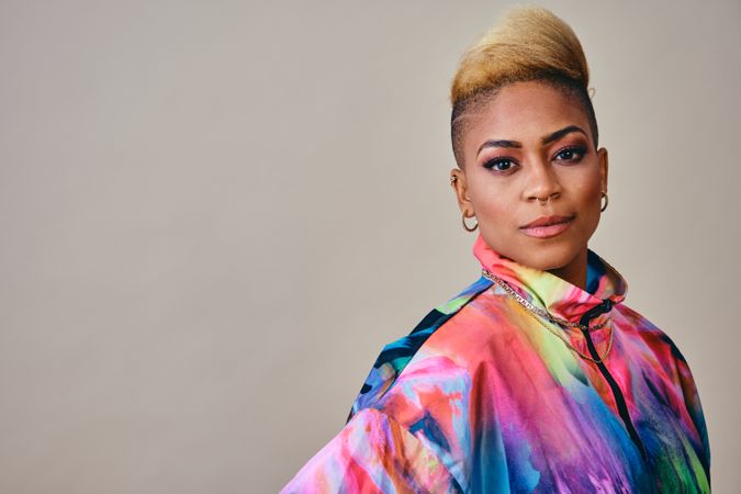 Studio shot of Black woman in bold 80s windbreaker jacket with copy space