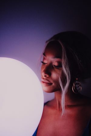 Black adult woman with illuminated balloon in darkness looking at camera