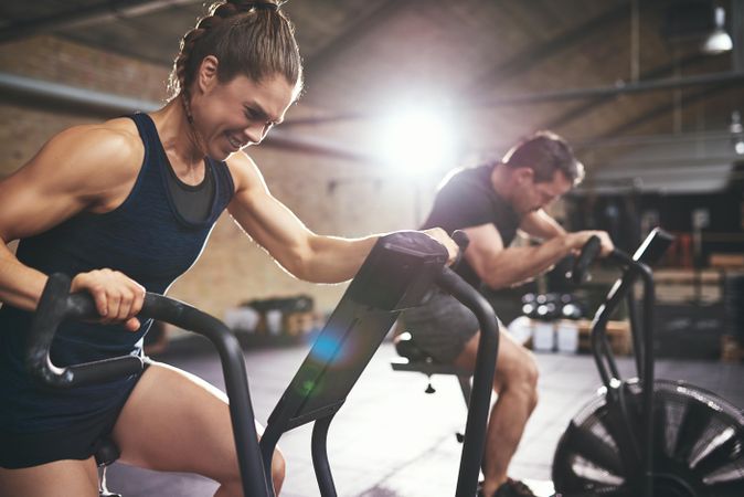 Energetic couple using exercise bikes to workout