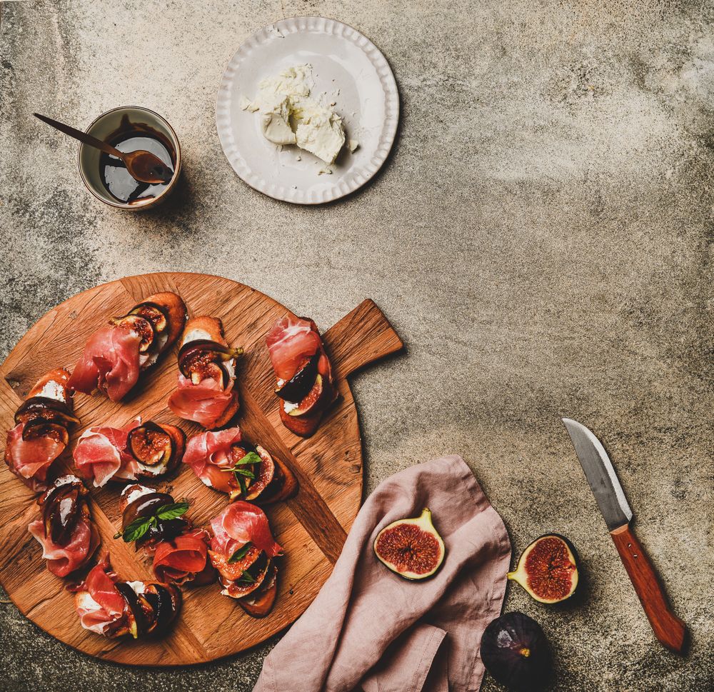 Crostinis with prosciutto, goat cheese and grilled figs, square crop, copy space
