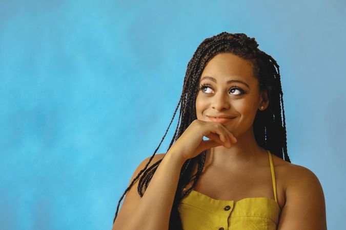 Portrait of female with long braided hair thinking about something in yellow clothes