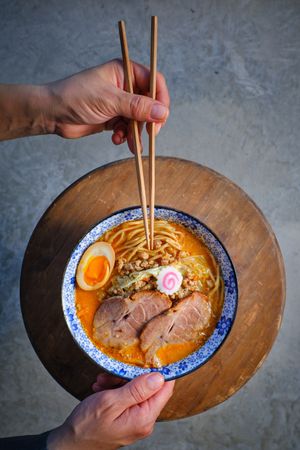 Faceless person having dinner with Asian noodle soup