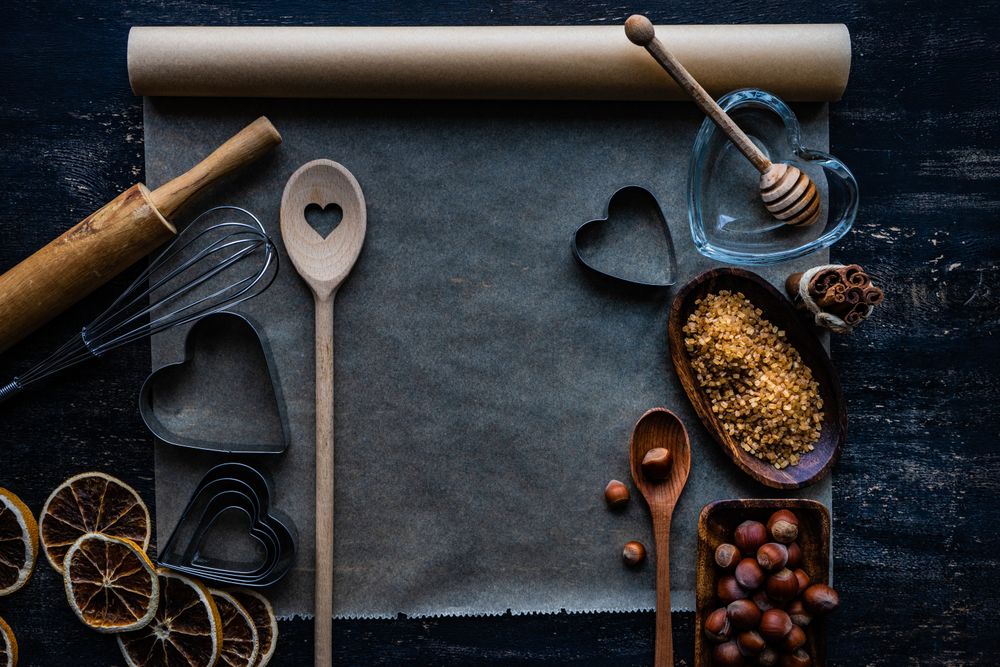 Heart shaped cookie cutters and baking equipment with ingredients in kitchen