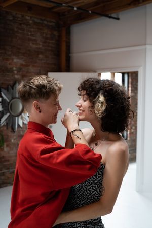 Two women share a big smile while looking at each other and holding hands