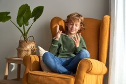Cheerful boy playing with colourful string at living room